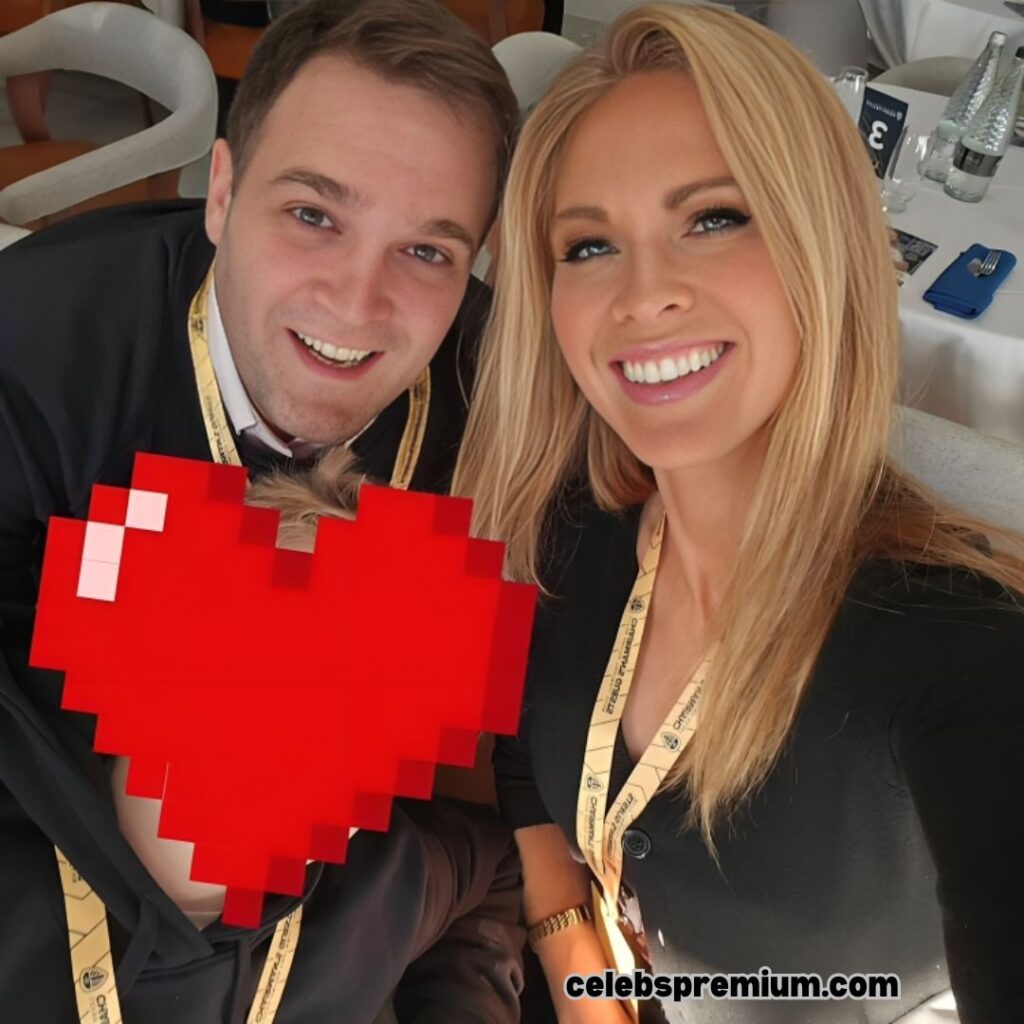 Jo Blythe is smiling in a selfie with her husband. Jo is wearing a black top and a gold necklace. Her husband is also smiling.