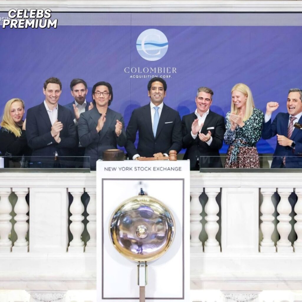 Omeed Malik and several other individuals are pictured at the New York Stock Exchange for the Colombier Acquisition Corp. event. They are standing behind a podium with a bell, and a screen in the background shows the company's logo. The group appears to be celebrating.